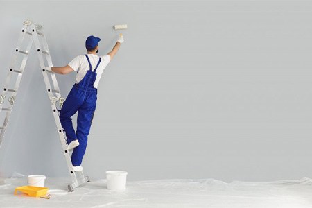 A contractor painting the interior walls of a house
