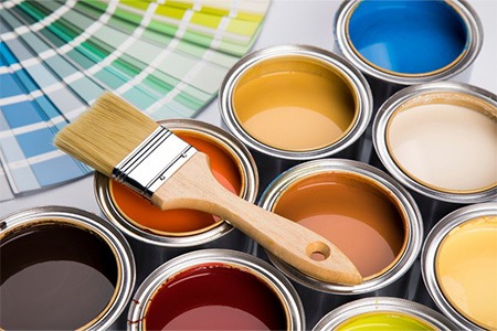 A paintbrush atop several paint cans
