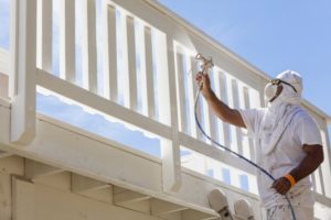 person painting the deck of a patio outside